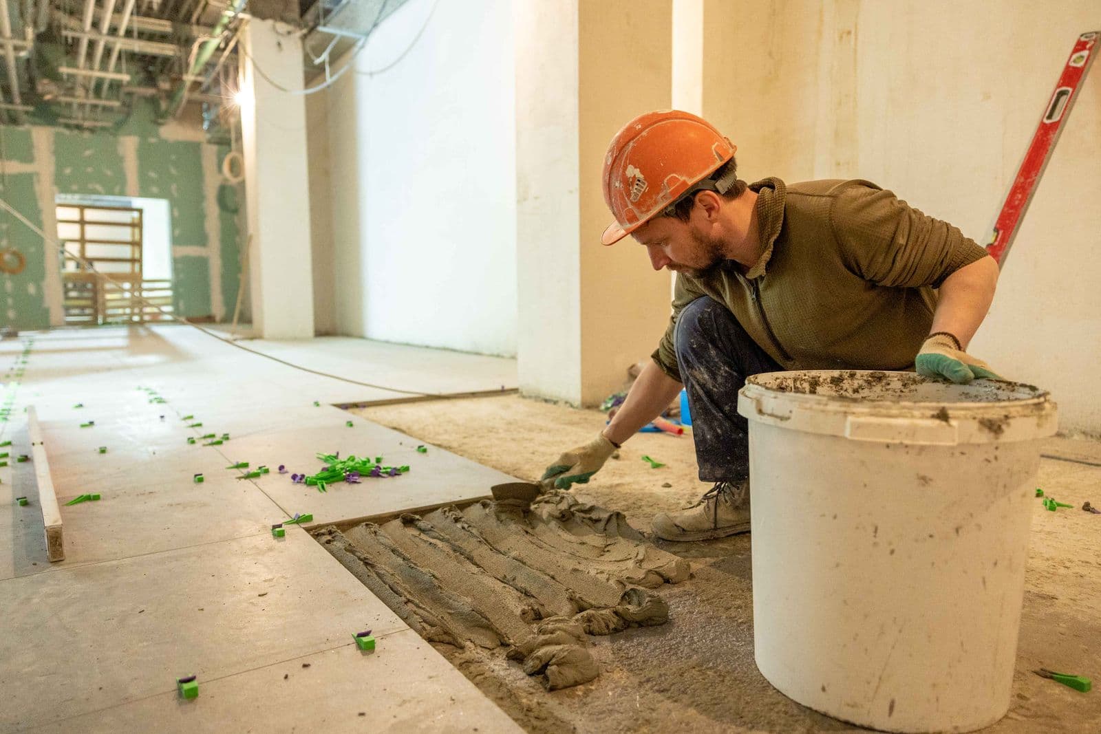 Oficial instalando piso en enchape durante una obra de acabados — foto ilustrativa